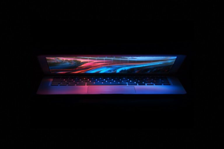 a laptop in the dark with a colorful background